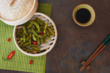 Spicy Edamame beans served warm with salt in bamboo steamer. Top view, blank space