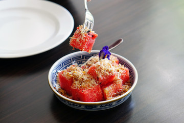 Watermelon with Sweet Dried Fish-Crispy Shallot Dip - Fresh Watermelon chunks thoroughly speckled with a sugary dip of dried fish flakes and crispy shallots, Royal Thai cuisine, Selective Focus.