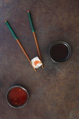 Vietnamese rice paper roll .Minimalist composition of  sushi roll, chopsticks, chili and soy sauce. Top view, blank space