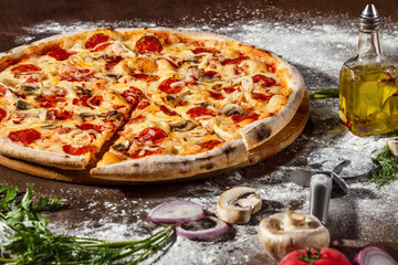 Italian pizza with pepper, cheese, mushrooms and salami at rustic wooden desk background. Closeup...