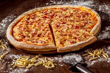 Closeup image of tasty italian pepperoni pizza with ham at wooden table background.