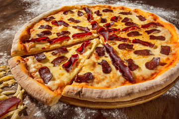 Closeup image of tasty italian pepperoni pizza with salami at wooden table background.