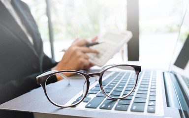 business executive working on caculator selective focus on eyeglasses
