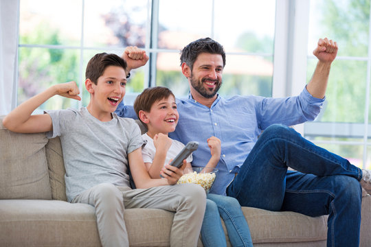 Father and sons watching tv at home
