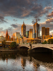 Obraz premium Melbourne City, Yarra River, Princes Bridge with Reflection Cityscape Skyline background under dramatic Golden Sky Sunset, Australia