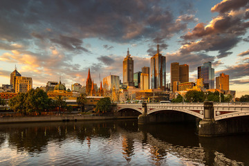 Fototapeta na wymiar Melbourne City, Yarra River, Princes Bridge with Reflection Cityscape Skyline background under dramatic Golden Sky Sunset, Australia
