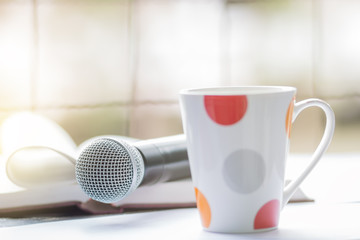 White and red cup coffee against microphone on abstract blurred window on table, pastel tone