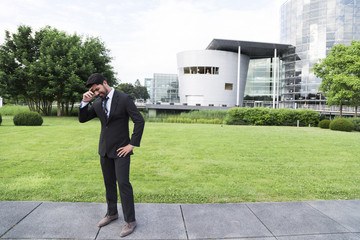 Successful businessman or worker standing in suit near office building