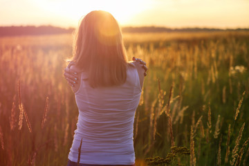 Young girl hugging herself on a sunny field. Instagram