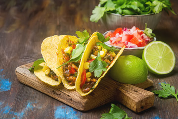 Traditional Mexican tacos with tomatoes, meat, herbs. Dark background. Fast food.