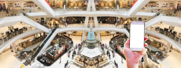 Fototapeta na wymiar Abstract blurred people walking for shopping in the big department store with hand holding smartphone with panoramic view - Online shopping of concept