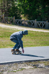 Teenage boy rides a skateboard on the asphalt road