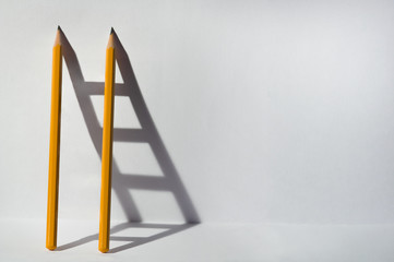 Two pencils and a shadow in the form of staircase. Teamwork and solving problems business concept.