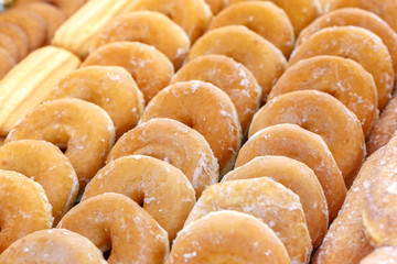 Pile of delicious donuts with sugar background.