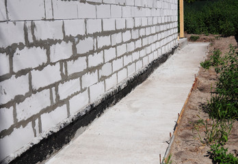 Waterproofing and insulation unfinished house foundation wall. Waterproofing house foundation with...