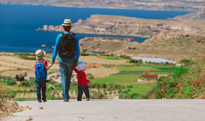 Fototapeta na wymiar father with two kids walking on scenic road