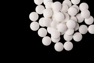 white pills on black glass background