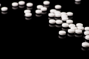 white pills on black glass background