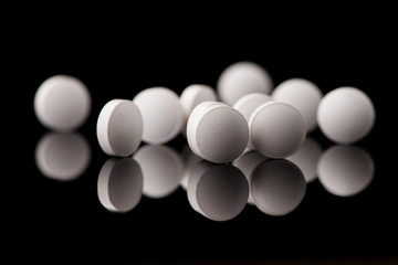 white pills on black glass background