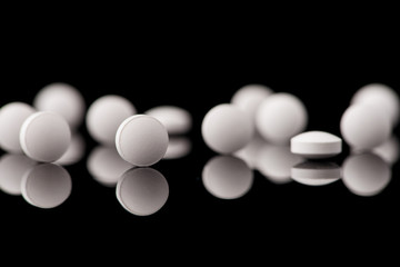 white pills on black glass background