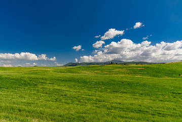 Fototapeta premium Perfect panorama of green hills with blue sky and fluffy clouds