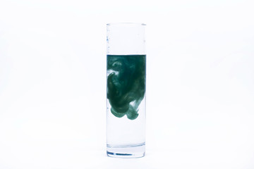 Blue paint falls in a glass with water