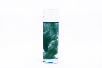 Blue paint falls in a glass with water
