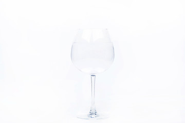 Crystal wineglass with water stands on white background