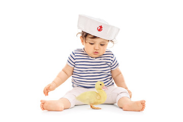 Baby girl in a sailor outfit with a small duckling
