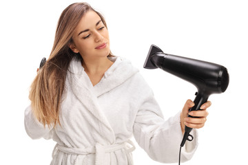 Girl in a bathrobe blowing her hair with a hairdryer