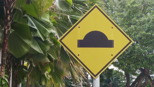 Braking, reduce speed. Road sign "speed hump" in Malaysia. Zoom in.