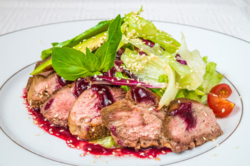 Tasty, appetizing pieces of chopped meat with sauce, tomatoes and herbs, on a white plate. Horizontal frame