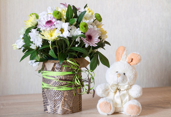 Bouquet of different chrysanthemums in paper with bow on wood.