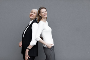 Two beautiful smiling women standing together, young and senior people