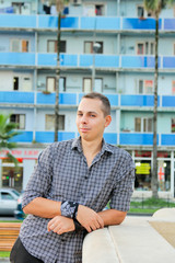 Human emotion portrait. Laugh young man looking at the camera. Man in shirt standing in the city