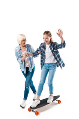 grandmother and happy granddaughter with skateboard isolated on white in studio