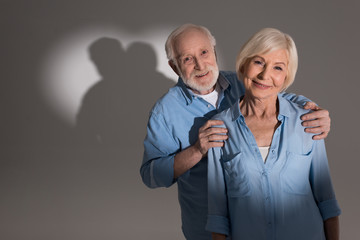 senior couple standing in studio with heart shaped shadow
