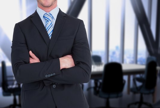 businessman crosses his arms against office background 