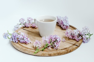Obraz na płótnie Canvas Cup of tea with lilac spring flowers on the wood table. White background