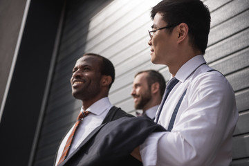 young stylish multiethnic businessmen in formalwear standing outdoors, business team meeting