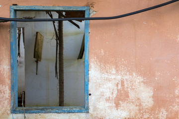 old wooden blue window frame on an orange wall of an abandoned house - horizontal