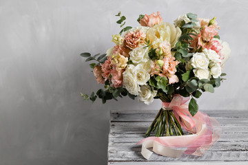Bridal vintage bouquet. The bride's . Beautiful of mixed flowers and greenery, decorated with silk ribbon, lies on vintage wooden table. vintage style