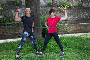 Seniorenpaar Mann  und Frau , 50Plus,  machen Fitness&uuml;bungen in der Natur mit Band und Hantel