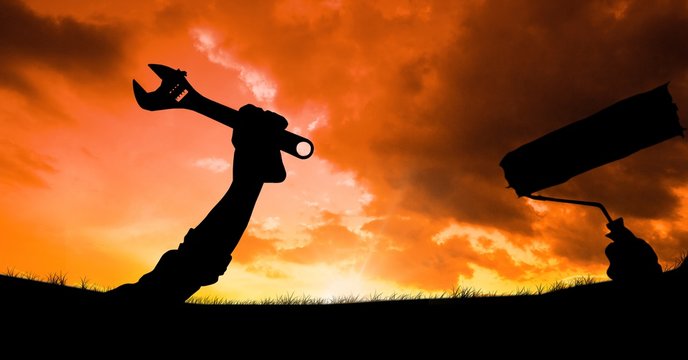 Silhouette hands holding tools against sky during sunset