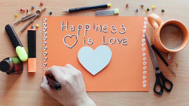 Hand drawn time lapse of hand writing phrase “Happy Valentines day!” and cutting heart from paper. Photo sequence animation. Expression of feelings through art. Love makes people better.