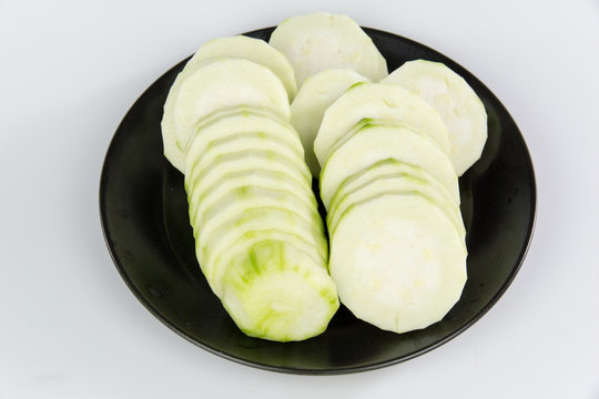 slices of Loofah on a black plate isolated on white background
