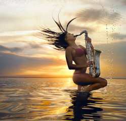 Young sexy woman with sax with splash of water against sunset background - obrazy, fototapety, plakaty