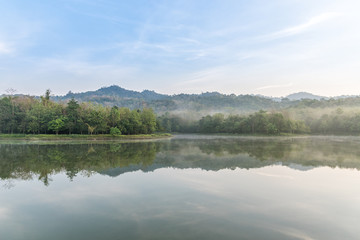 Fog is covered Lake and rain forest on cloudy morning.