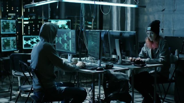 Team of Internationally Wanted Boy and Girl Hackers Organize Advanced Virus Attack on Corporate Servers. Place is Dark and Has Multiple displays. Shot on RED EPIC-W 8K Helium Cinema Camera.