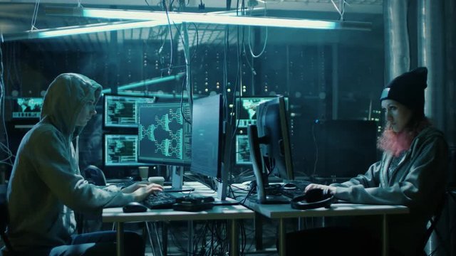  Team of Internationally Wanted Boy and Girl Hackers Organize Advanced Virus Attack on Corporate Servers. Place is Dark and Has Multiple displays.Shot on RED EPIC-W 8K Helium Cinema Camera.